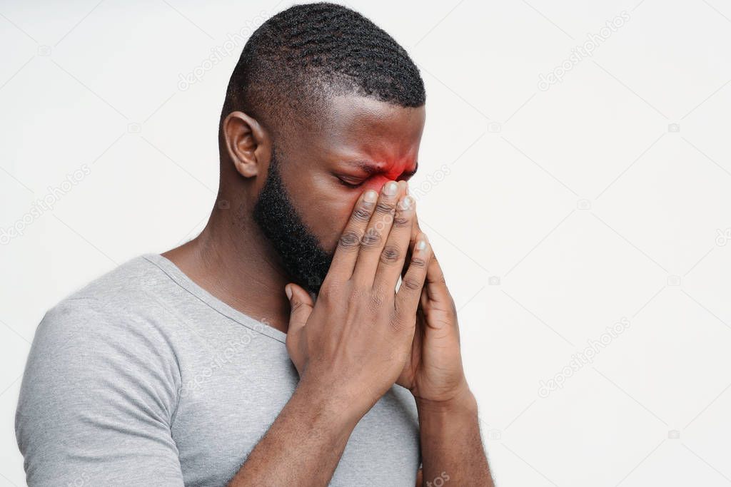 Exhausted black guy suffering from antritis, rubbing nose bridge