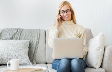 Laptop kullanarak orta yaşlı kadın yönetici projesini evden yönetiyor.