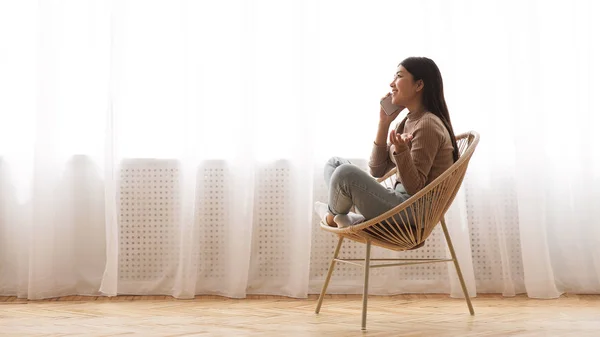Menina feliz falando no telefone, sentado em poltrona moderna — Fotografia de Stock