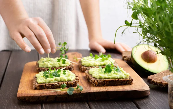 Girl preparing sandwiches with avocado spread and microgreen — Stock Photo, Image