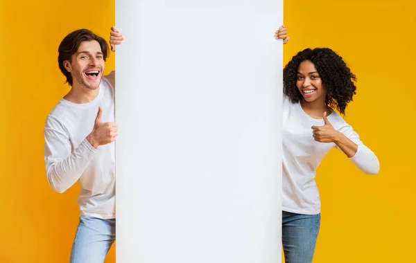 Felice interrazziale coppia holding bianco pubblicità bordo e mostrando pollice su — Foto Stock