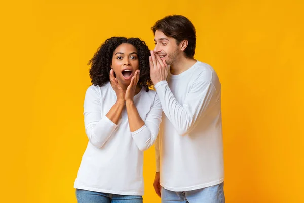 Millennial kille viskar hemlighet eller skvaller till överraskad svart flicka — Stockfoto