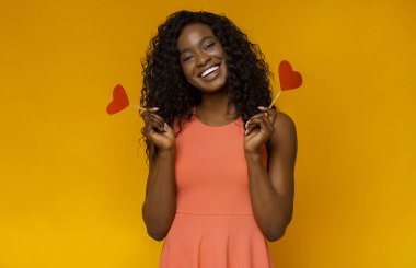 Sarı arka planda kırmızı kalpli tatlı Afrikalı kız
