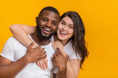 Sarı arka planda poz veren romantik ırklar arası çift portresi