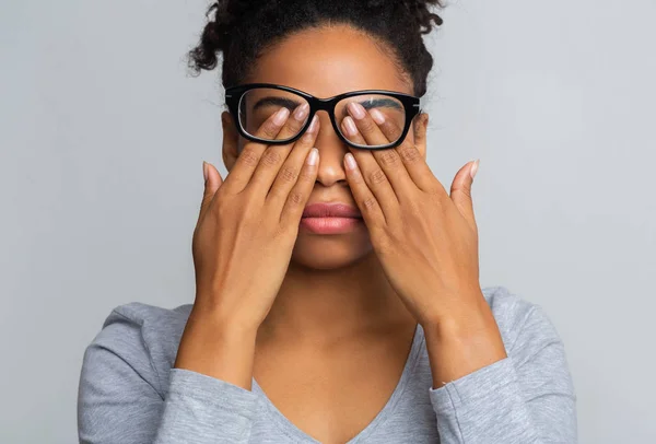 Fille noire dans les lunettes frotte les yeux, souffrant d'yeux fatigués — Photo