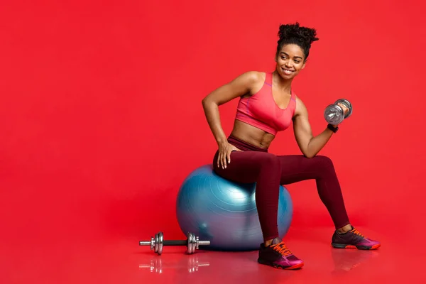 Fitness ragazza che si allena con i bilancieri, seduto sulla palla fitness — Foto Stock