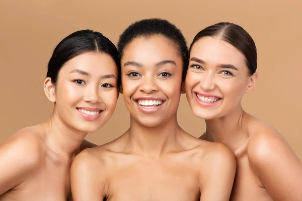 Drie multiculturele dames modellen poseren glimlachen op Beige Studio achtergrond — Stockfoto