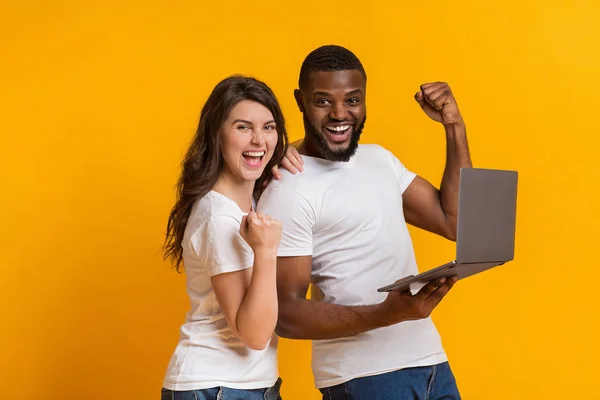 Heureux couple multiracial réjouissant succès avec ordinateur portable — Photo