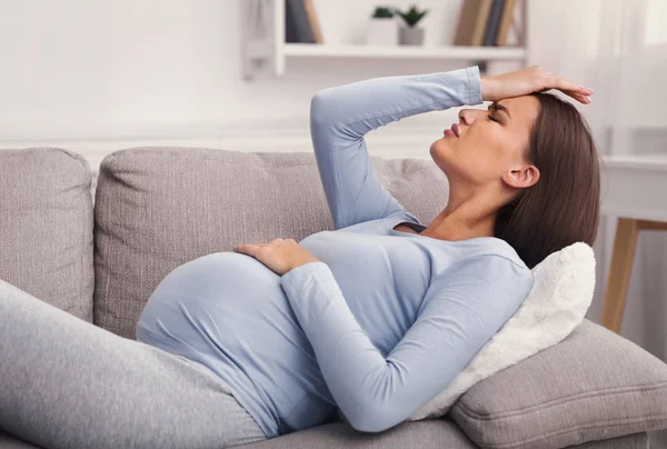 Schwangere leidet unter Kopfschmerzen, wenn sie zu Hause auf Couch liegt — Stockfoto