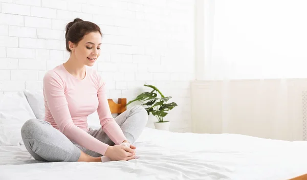 Mulher positiva aquecendo as pernas na cama, panorama — Fotografia de Stock