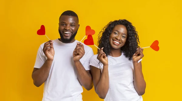 Encantador casal afro segurando cartões em forma de coração vermelho — Fotografia de Stock