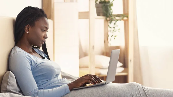 Ragazza afro-americana che utilizza il computer portatile seduto a letto, Panorama — Foto Stock