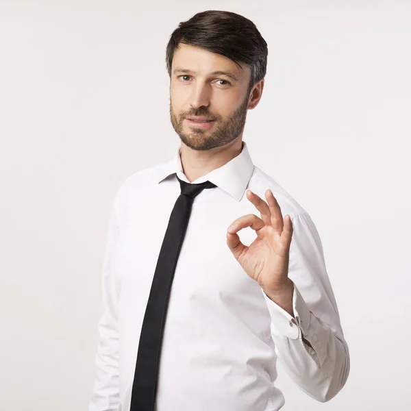 Empresario positivo haciendo gestos OK Sonriendo de pie en el estudio, aislado — Foto de Stock