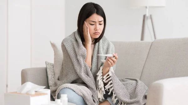 Ziek meisje met hoofdpijn controleren thermometer, zitten op de bank — Stockfoto