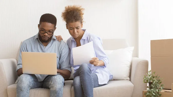 Afro Cónyuges Usando Laptop Reading Property Papers Sentados en el sofá —  Fotos de Stock
