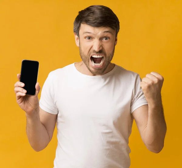 Man Shaking Fists Holding Phone Celebrating Over Yellow Background, Mockup — Stok Foto