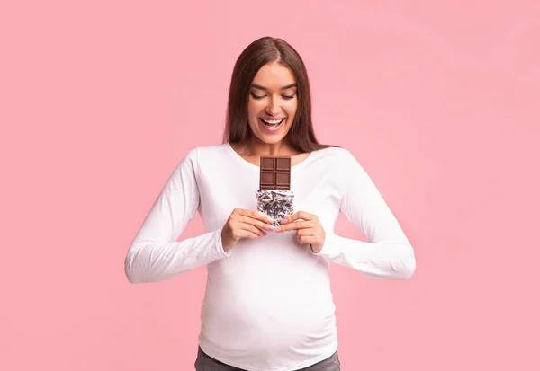 Wanita hamil Makan Coklat Di Latar Belakang Studio Merah Muda — Stok Foto