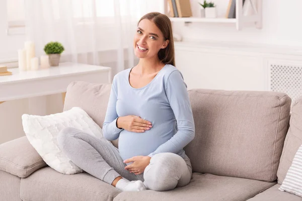 Hamil Girl Touching Belly Smiling Sitting On Couch At Home — Stok Foto