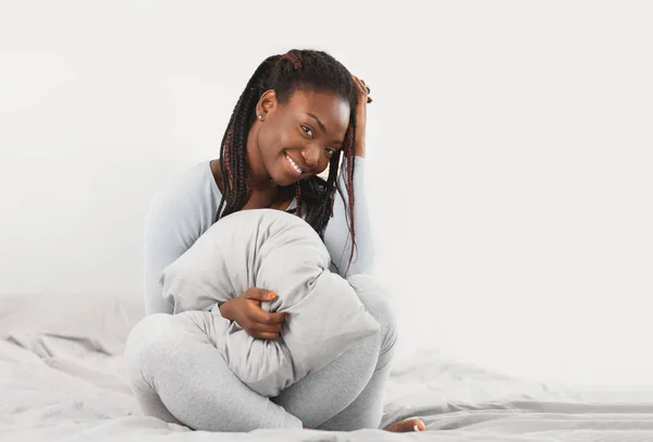 Africano americano chica celebración manta posando sentado en cama interior —  Fotos de Stock