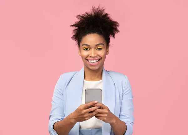 Usmívající se afro dívka pomocí mobilního telefonu při pohledu do kamery — Stock fotografie