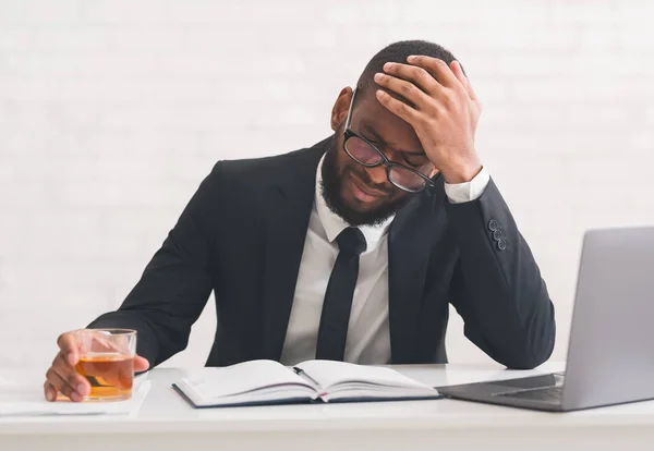 Estresado empresario afro beber whisky en el lugar de trabajo —  Fotos de Stock