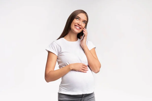 Sorrindo grávida mulher falando no celular sobre branco estúdio fundo — Fotografia de Stock