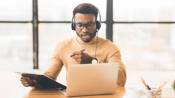 Concentré afro-américain guy dans headset écriture notes — Photo