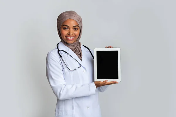 Schwarze muslimische Ärztin hält digitales Tablet mit schwarzem leeren Bildschirm — Stockfoto