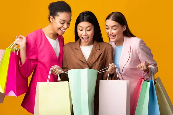 Tre upphetsade flickor tittar in i Shopper väskor, Studio Skott — Stockfoto