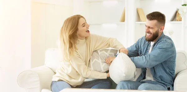 Playful millennial couple fighting by pillows, having fun — Stock Photo, Image