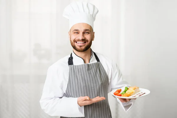 Šéfkuchař drží talíř s pečeným lososem steak stojící v kuchyni — Stock fotografie