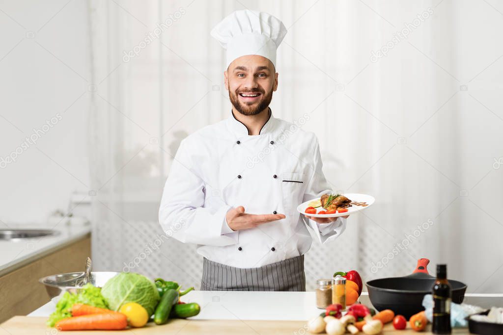 Cook Man Holding Plate With Chicken Presenting Dish In Kitchen
