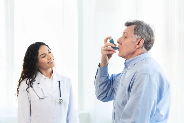Az érett férfit kék asztma inhalátorral vizsgáló orvos — Stock Fotó