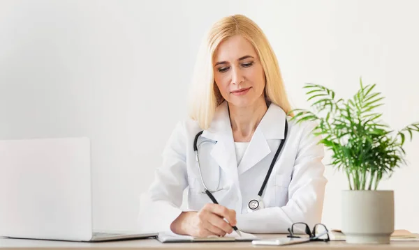 Doctor lady prescribing course of treatment, sitting at workplace — Stock Photo, Image