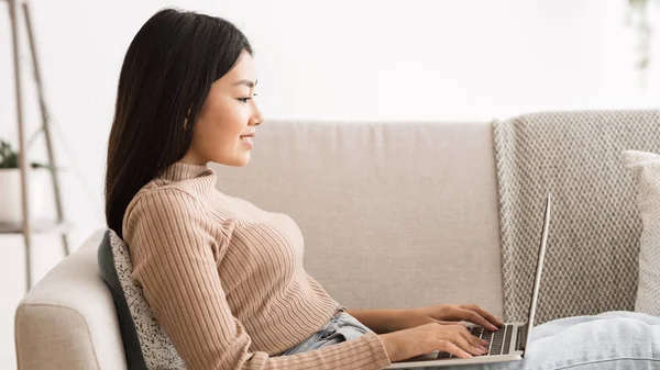Mujer joven websurf en el ordenador portátil, relajarse en el sofá en casa —  Fotos de Stock