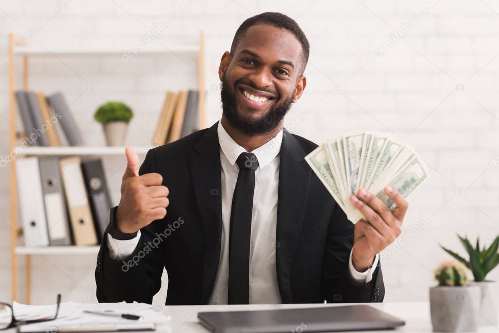 Smiling successful black businessman holding bunch of money