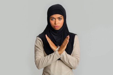 Siyahi Müslüman kadın inkar hareketi yapıyor, kollarını kavuşturuyor, bir şeyi reddediyor.