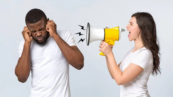 Naštvaná žena křičí na svého přítele s reproduktorem přes světlo pozadí — Stock fotografie