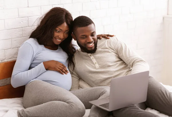 Happy pregnant couple choosing furniture for baby room online — 스톡 사진