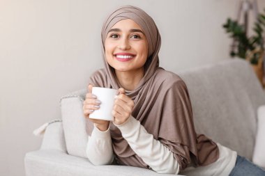 Mutlu Müslüman kız evde çayla rahatlıyor.