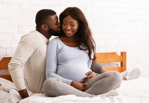 Glada unga gravida par kramas i sängen hemma — Stockfoto