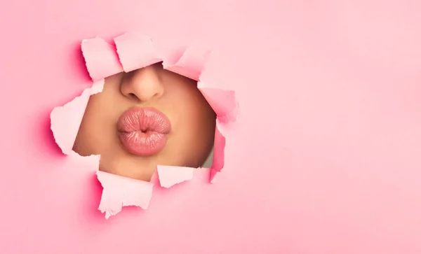 Woman pouting plump bright lips, peep into slit of paper — Stock Photo, Image