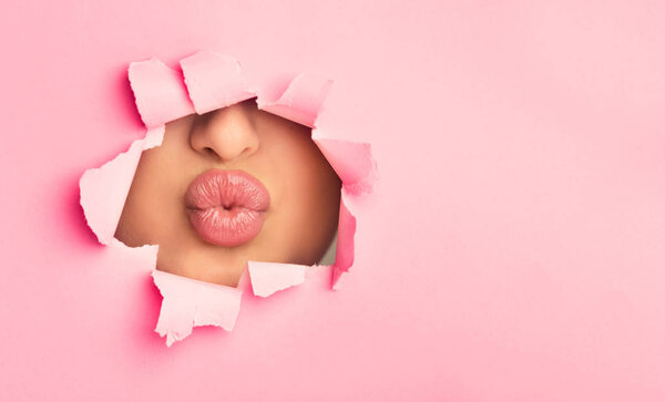 Woman pouting plump bright lips, peep into slit of paper