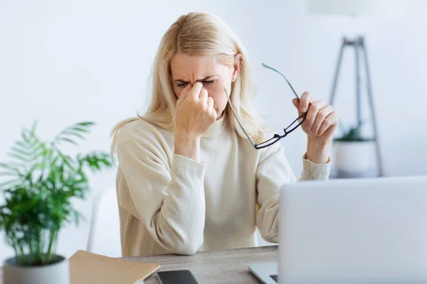 Müde Geschäftsfrau massiert Nasenrücken, arbeitet am Laptop — Stockfoto