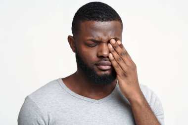 Sad black guy touching his eye, suffering from conjuctivitis clipart