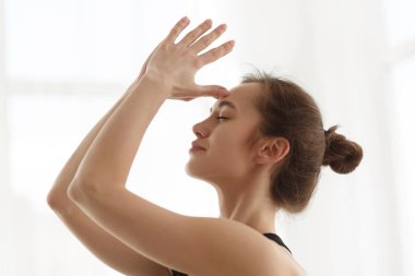 Elleri alnında meditasyon yapan bir kız.