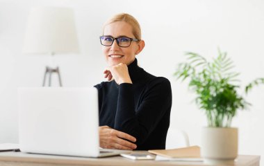 İnternette çalışan neşeli öğretmen kameraya gülümsüyor.