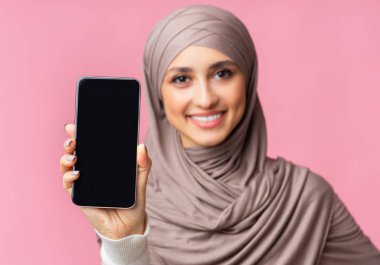 Gülümseyen Arap kadının ellerinde siyah ekranlı modern akıllı telefon.