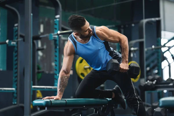 Hombre fuerte entrenando bíceps con mancuernas en el gimnasio —  Fotos de Stock