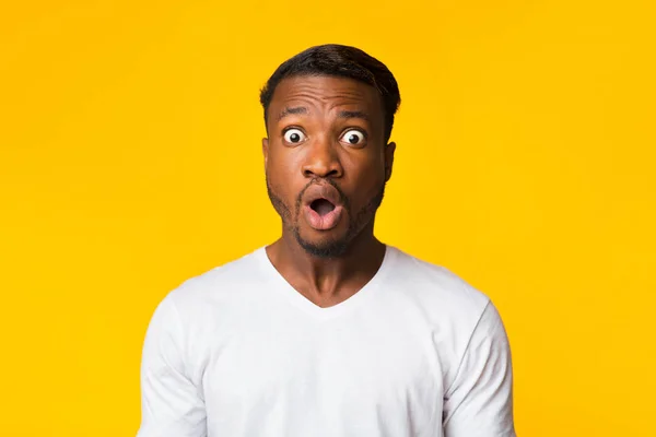 Afro ragazzo guardando fotocamera a sorpresa su sfondo giallo — Foto Stock